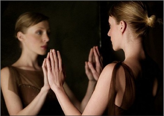 Woman looking in mirror .